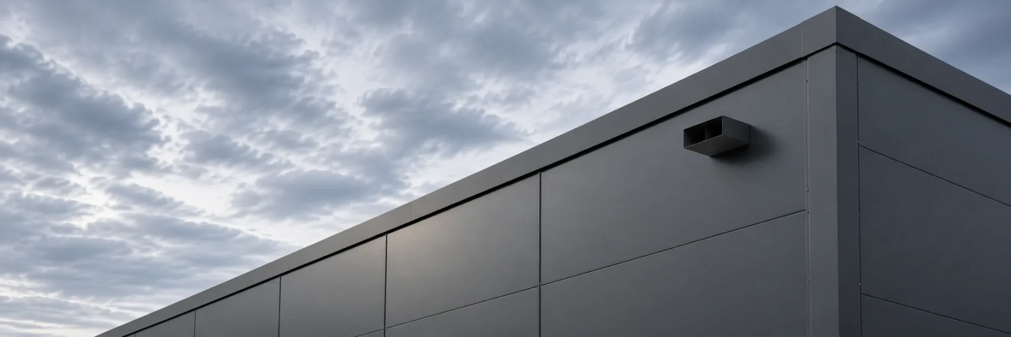 Illustrative visualisation: graphite industrial building facade with a small emergency overflow under the parapet